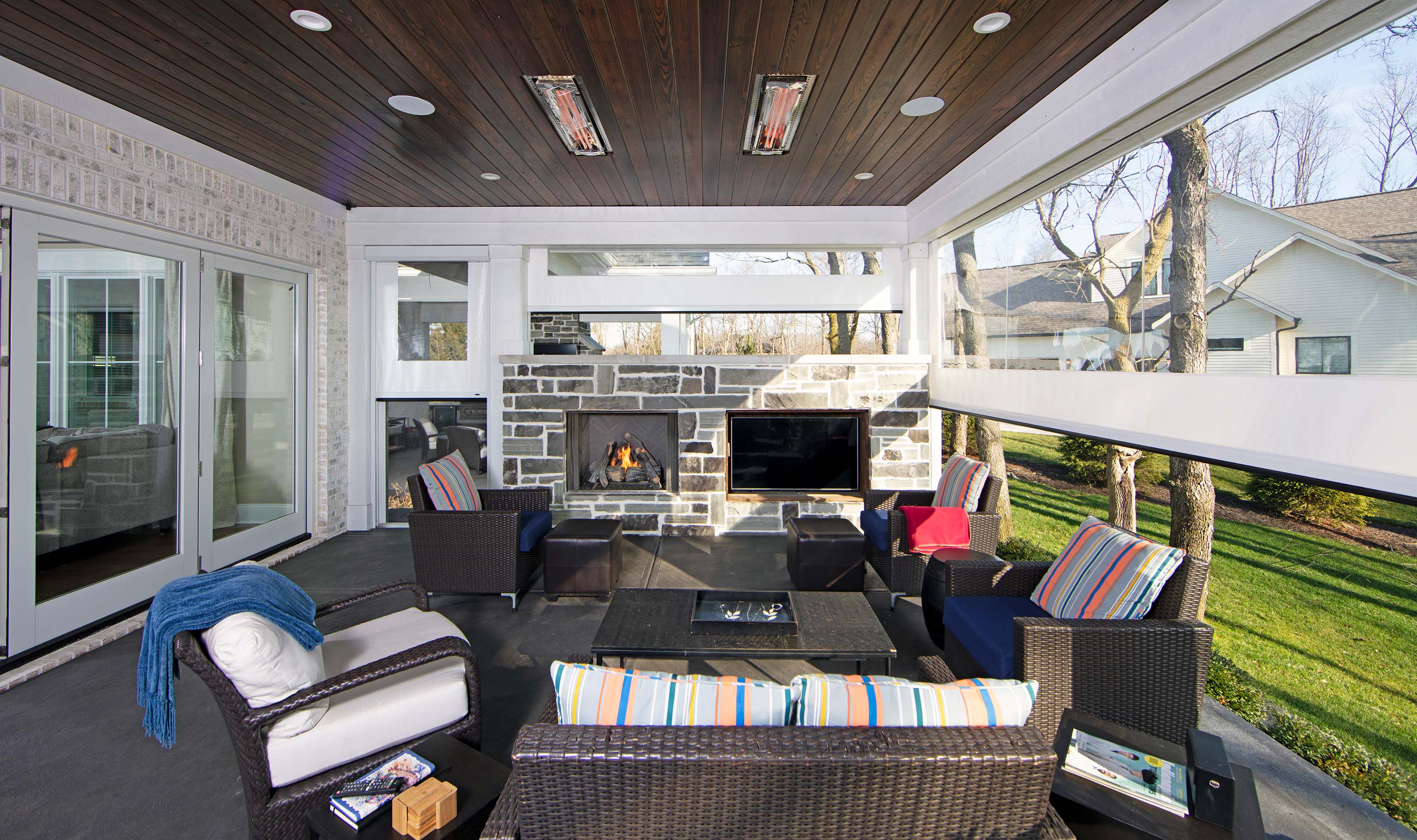 patio with vinyl screens and grey bricks surrounding a TV and fireplace