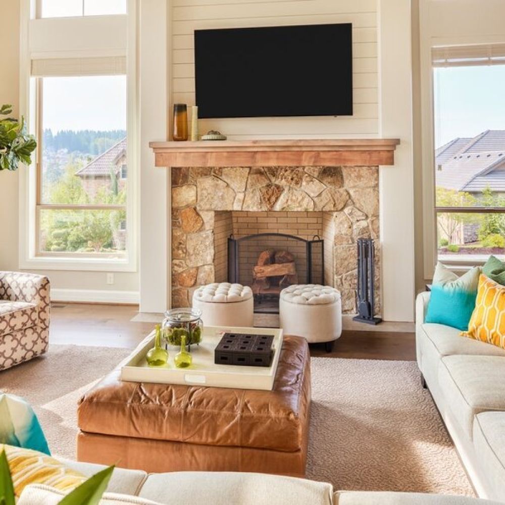 <span class="uk-h4">A family room living area with seating and a mounted TV above a fireplace between two windows.</span>
